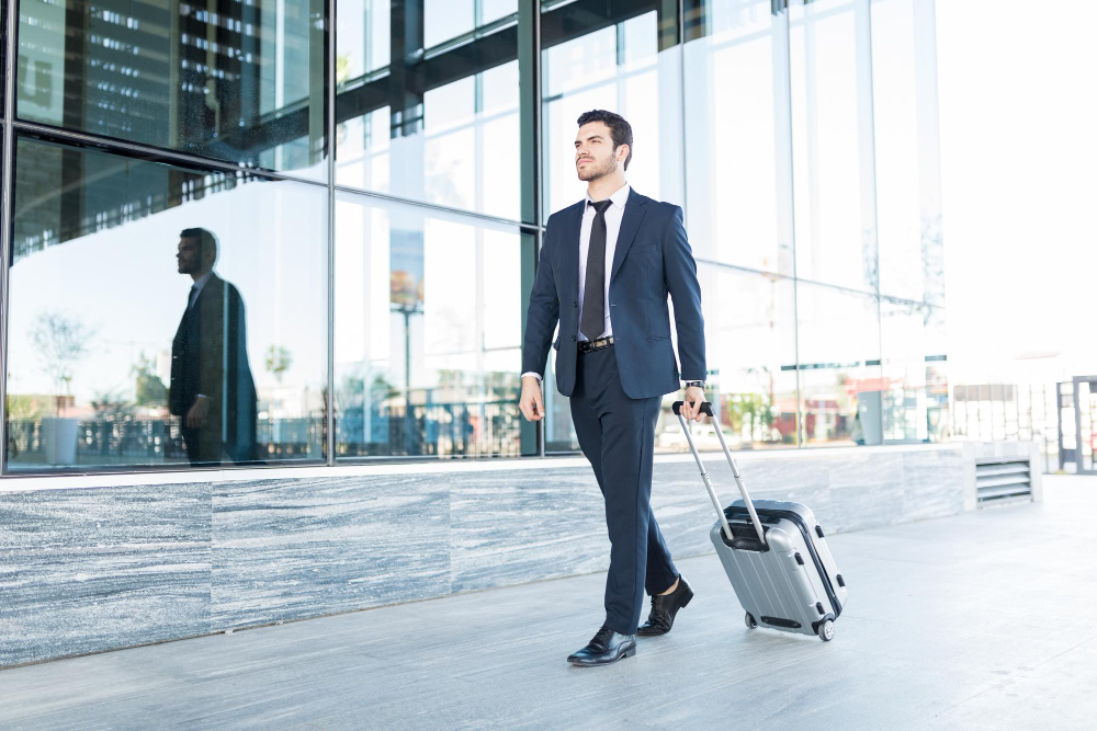 full-length-handsome-young-man-suit-walking-with-luggage-outside-office-building